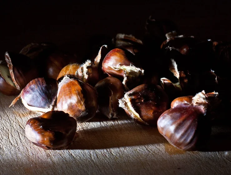 Castañas asadas con la cáscara abierta sobre una superficie de madera; fotografía de referencia tomada fuera de Canarias